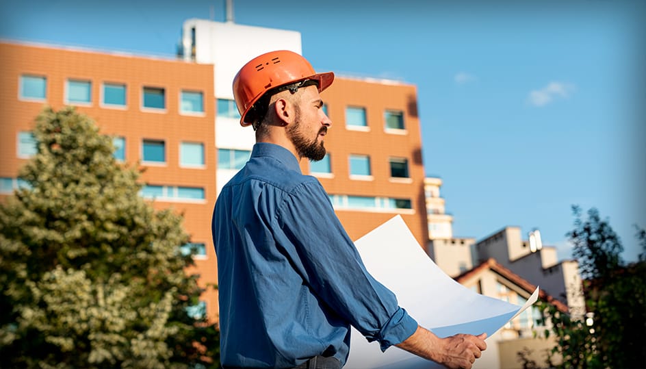 Bouwprofessional bekijkt bouwtekening buiten bij een woningproject. Deskundige voorbereiding en uitvoering door FB Bouwdiensten.