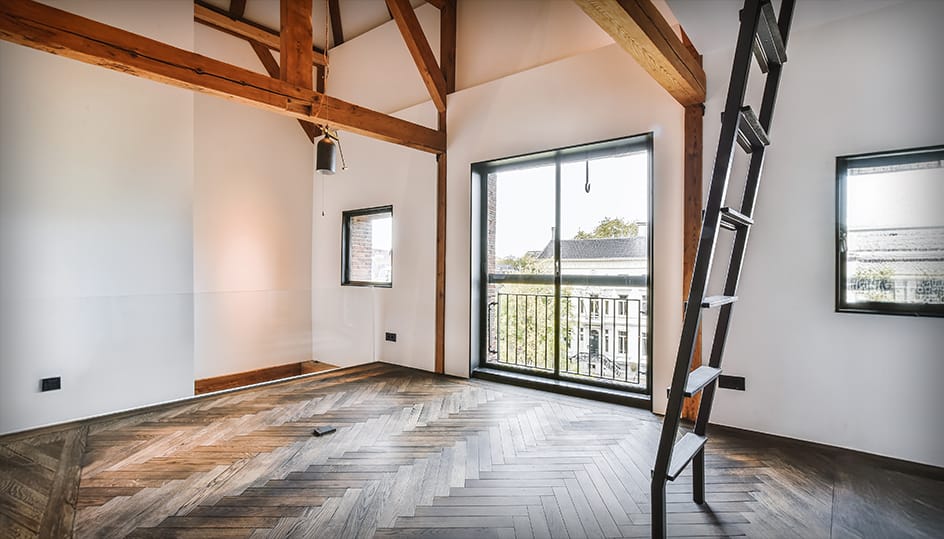 Afgewerkte zolderruimte met houten balken en modern parket. Stijlvolle renovatie en hoogwaardig eindresultaat door FB Bouwdiensten.