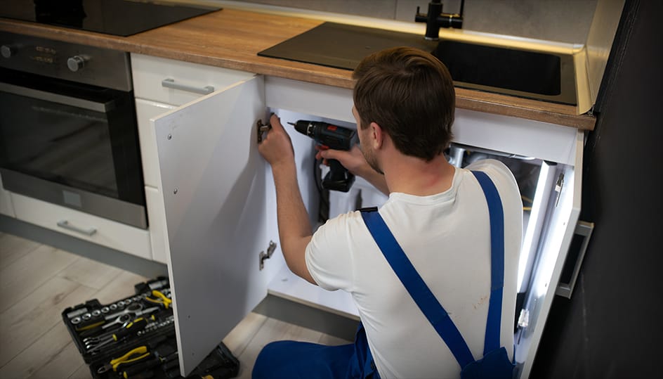 Monteur installeert keukenkastje tijdens renovatie. Professionele plaatsing en nette afwerking door FB Bouwdiensten.