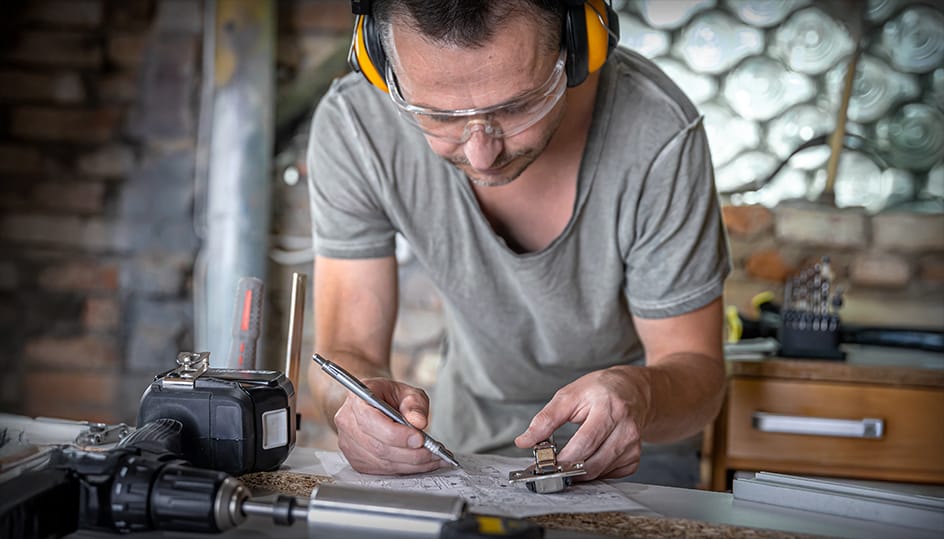 Vakman werkt geconcentreerd aan projectplan in werkplaats. Nauwkeurige voorbereiding en vakmanschap door FB Bouwdiensten.