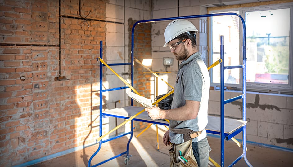 Bouwvakker bekijkt bouwtekening tijdens renovatieproject. Betrouwbare samenwerking en vakkundige uitvoering door FB Bouwdiensten.