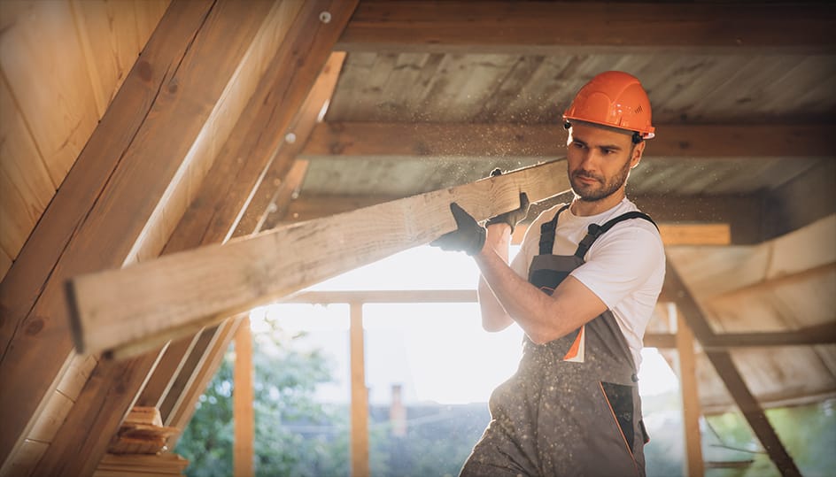 Bouwvakker tilt houten balk tijdens renovatie. Sterk vakmanschap en betrouwbare uitvoering door FB Bouwdiensten.