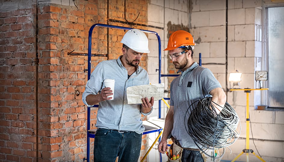 Twee bouwprofessionals bespreken renovatieplan op locatie. Teamwork en deskundige aanpak door FB Bouwdiensten.