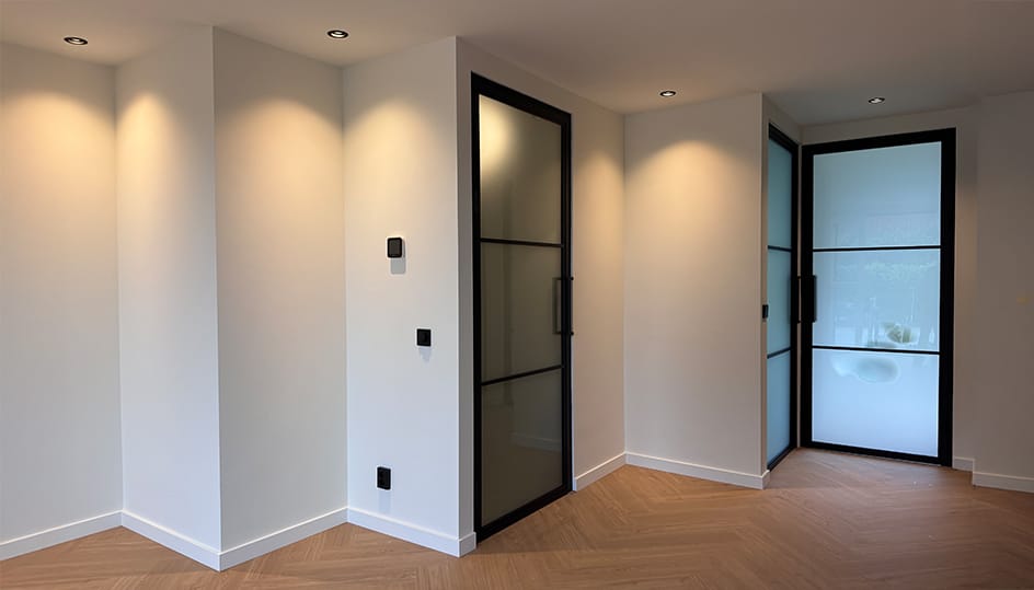 Afgewerkte moderne ruimte met stalen deuren en houten vloer. Strakke renovatie en hoogwaardig interieurwerk door FB Bouwdiensten.